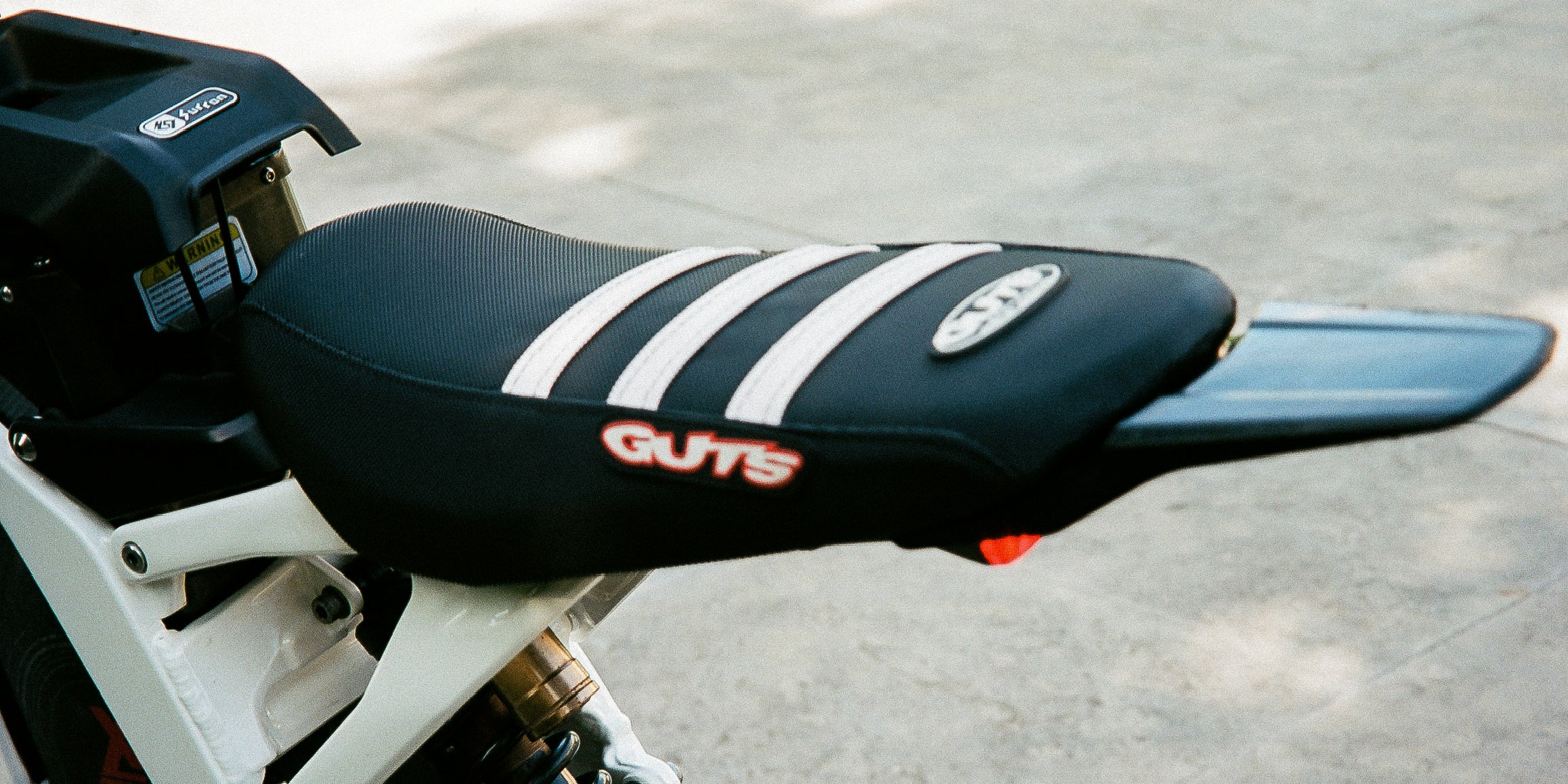 Guts Black/White Sur-Ron gripper seat cover installed on a custom built ebike.